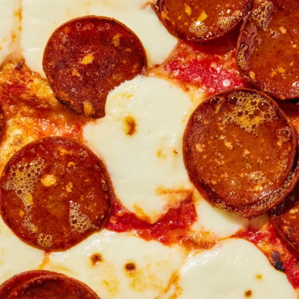 A close up of a pizza with vegan plant based pepperoni