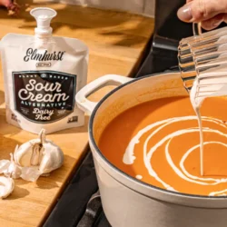 Elmhurst sour cream being poured in to a pot of pumpkin bisque