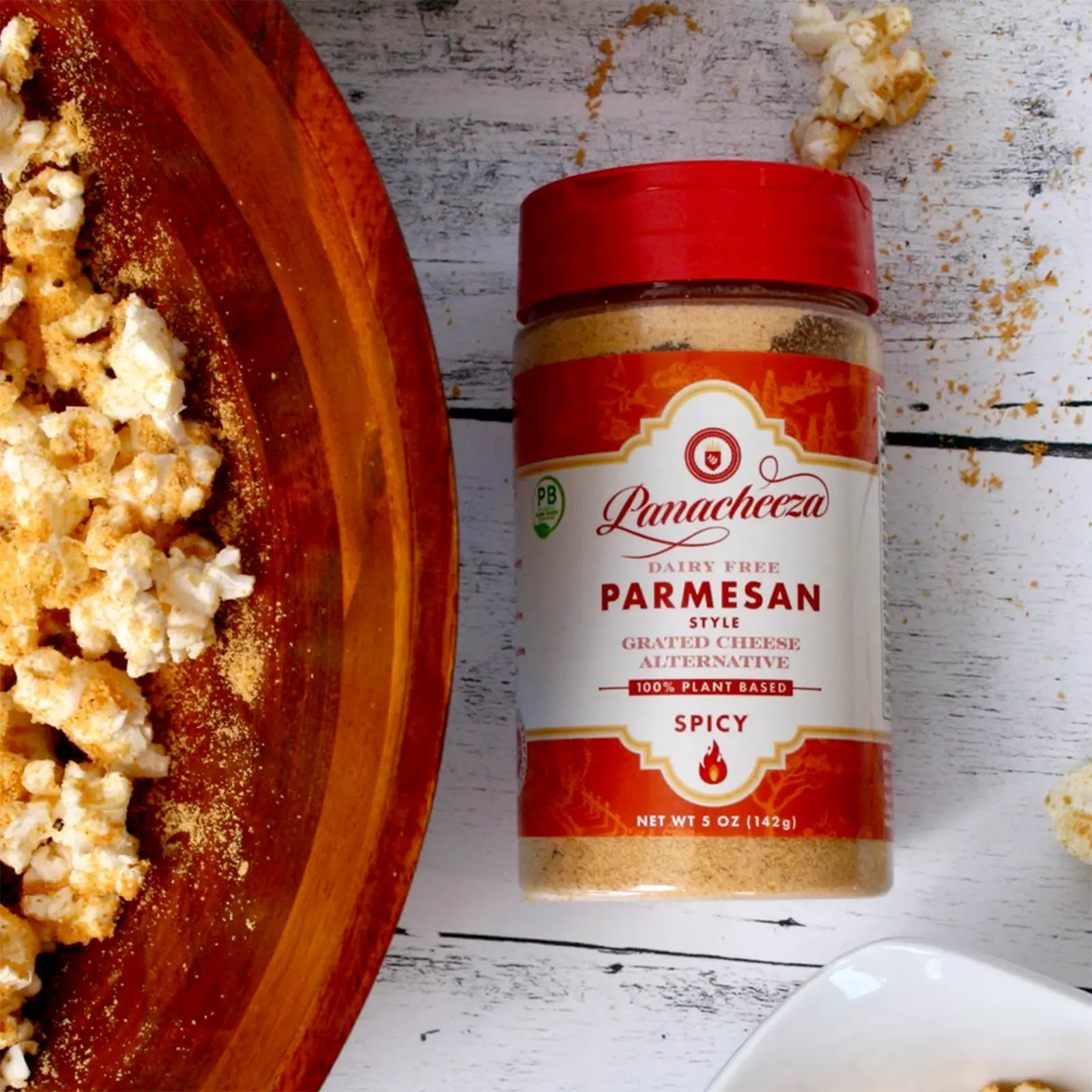 Spicy Vegan Parmesan on a table next to a bowl of popcorn