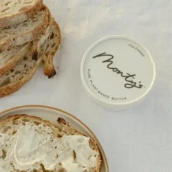 vegan butter on a white cloth with a side of several slices of bread and a plate of bread with butter