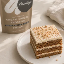 A piece of carrot cake next to a bag of Monty's frosting