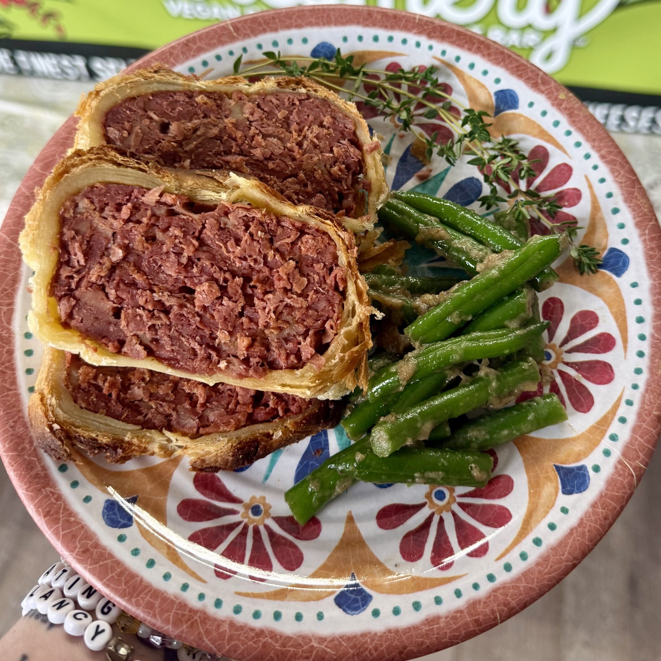 vegan beef Wellington on a plate with vegetables and a blurred background