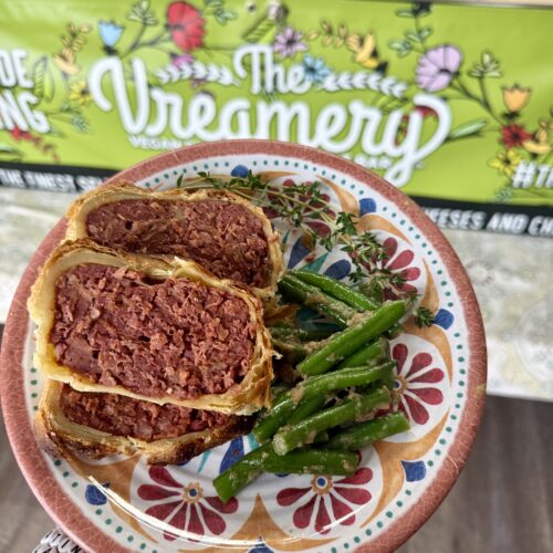 vegan roast on a plate with vegetables and a blurred background