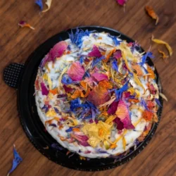 a round of vegan ash rind brie covered in edible flowers