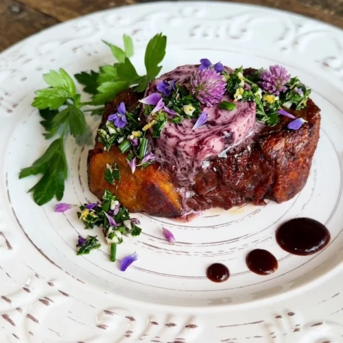 Seared and smoked vegan steak topped with purple wildflower gremolata and melting port wine butter